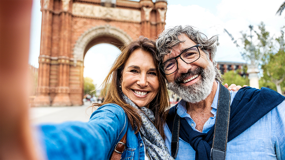 Middle aged couple taking a selfie in front of an arch.