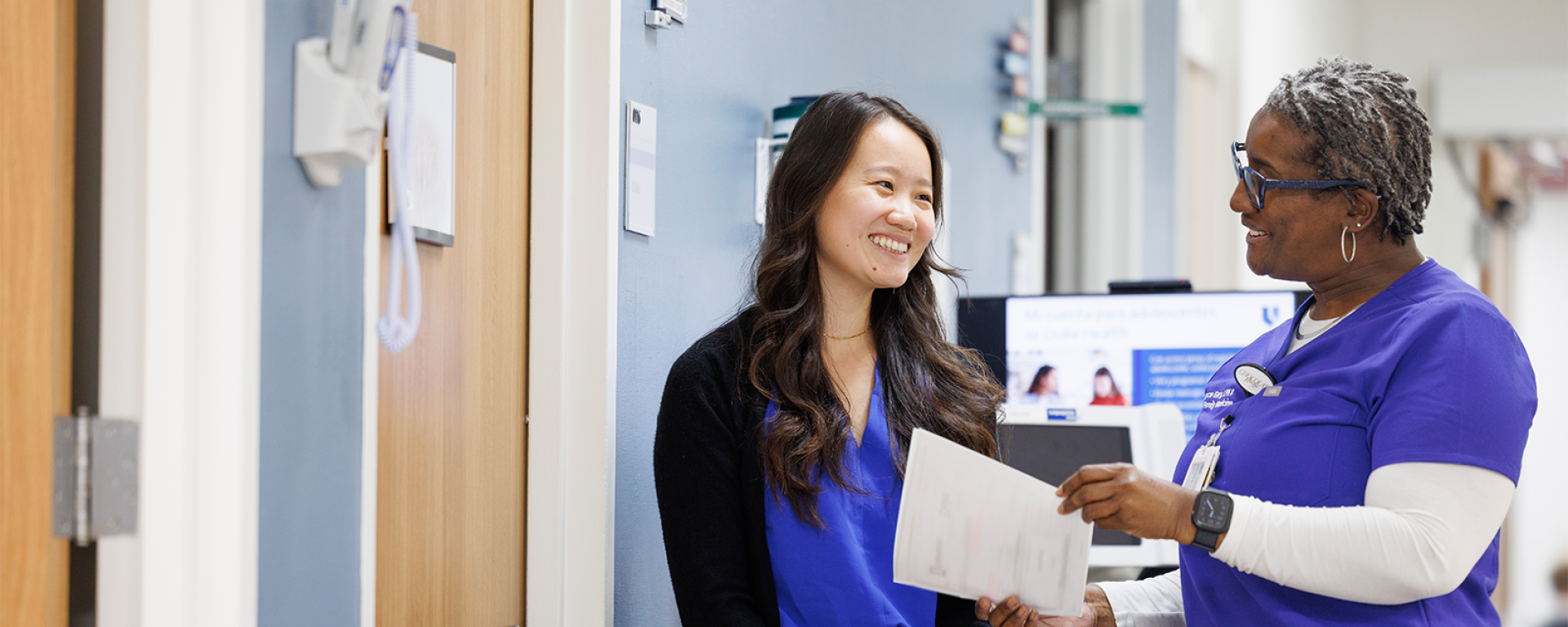 a faculty and staff member consultign outside a patient's door. 
